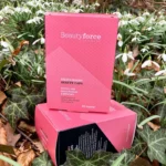 Pureday En æske med økologi silica boost skønhedskapsler hviler på en seng af grønne blade, med fokus på at fremme sundere hud, negle og hår. Emballagen er lys pink og indeholder 90 stk